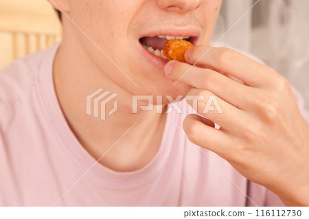 Caucasian man eating fried chicken pieces, American fast food culture, cooked chicken pieces 116112730