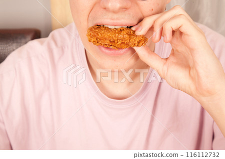 Caucasian man eating fried chicken wings, American fast food culture, cooked chicken pieces 116112732
