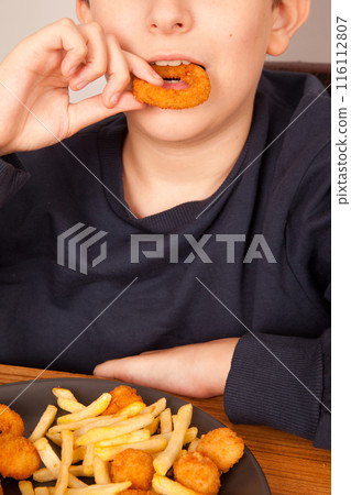 Caucasian man eats fresh fried onion rings with his hands, American fast food culture 116112807