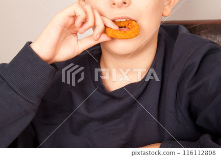 Caucasian man eats fresh fried onion rings with his hands, American fast food culture Caucasian man eats fresh fried onion rings with his hands, American fast food culture 116112808