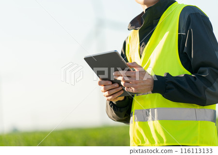 Engineer with digital tablet works on a field of wind turbines Engineer with digital tablet works on a field of wind turbines 116113133