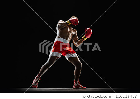 Confident athlete in red and white boxing shorts, preparing for next round, training isolated on black background Confident athlete in red and white boxing shorts, preparing for next round, training isolated on black background 116113418