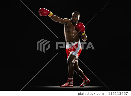 Dynamic pose. African-American muscular man with athletic strong body, boxer in motion isolated on black background Dynamic pose. African-American muscular man with athletic strong body, boxer in motion isolated on black background 116113467