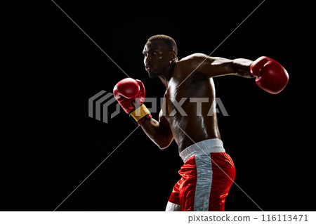 Muscular serious man, boxer with shirtless and sweating body training, punching isolated on black background Muscular serious man, boxer with shirtless and sweating body training, punching isolated on black background 116113471