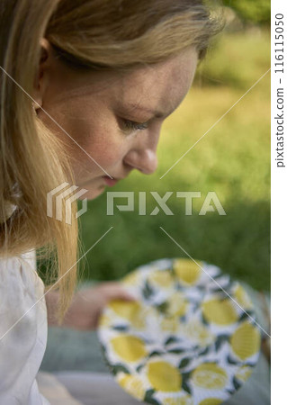 a beautiful young artist in a white dress paints a picture on the river bank a beautiful young artist in a white dress paints a picture on the river bank 116115050