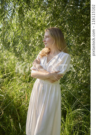 beautiful young artist in a white dress among the trees on the river bank beautiful young artist in a white dress among the trees on the river bank 116115102