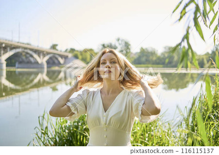 beautiful young artist in a white dress among the trees on the river bank 116115137