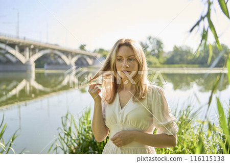 beautiful young artist in a white dress among the trees on the river bank beautiful young artist in a white dress among the trees on the river bank 116115138