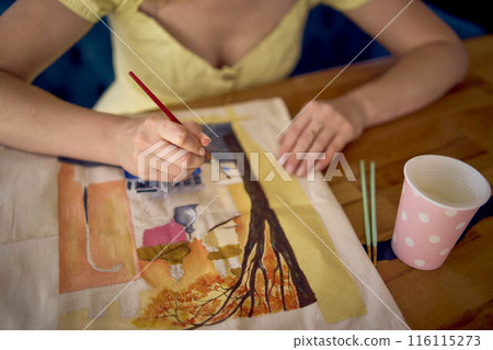 a beautiful young artist in a yellow dress paints a customized shopping bag a beautiful young artist in a yellow dress paints a customized shopping bag 116115273