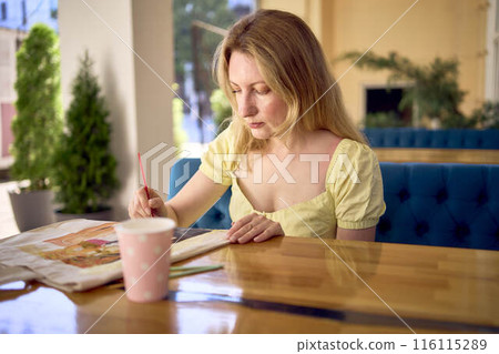 a beautiful young artist in a yellow dress paints a customized shopping bag 116115289