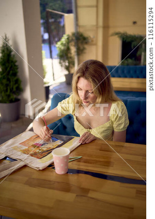 a beautiful young artist in a yellow dress paints a customized shopping bag a beautiful young artist in a yellow dress paints a customized shopping bag 116115294