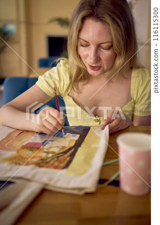 a beautiful young artist in a yellow dress paints a customized shopping bag 116115300