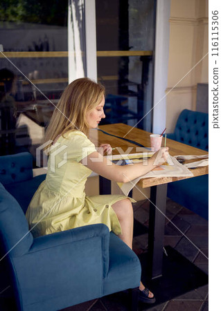 a beautiful young artist in a yellow dress paints a customized shopping bag a beautiful young artist in a yellow dress paints a customized shopping bag 116115306