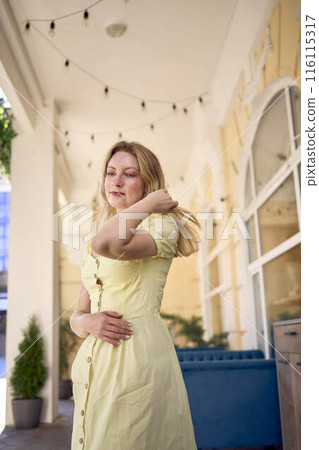 a beautiful young artist in a yellow vintage dress poses 116115317