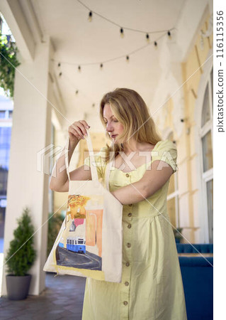 beautiful young artist in yellow dress posing with hand painted customized shopping bag beautiful young artist in yellow dress posing with hand painted customized shopping bag 116115356