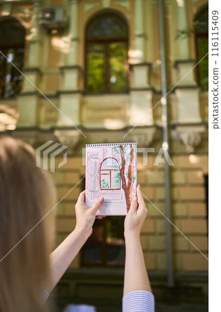 a young artist draws a sketch of a window on the streets of the city a young artist draws a sketch of a window on the streets of the city 116115409