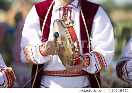 A musician in embroidery plays an ethnic drum. A musician in embroidery plays an ethnic drum. 116116411