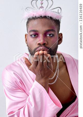 Lovely black american guy in pink shirt and crown flowing a kiss at camera, isolated 116116489