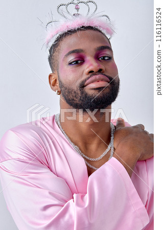 Glamorous black man in pink silk shirt looking pretty as proncess, with crown on head 116116524