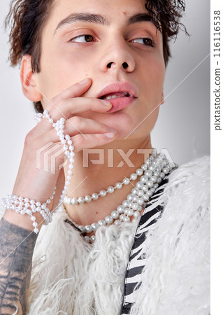 Close-up man with dark wavy hair, in necklace and fluffy jacket looking at side posing Close-up man with dark wavy hair, in necklace and fluffy jacket looking at side posing 116116538