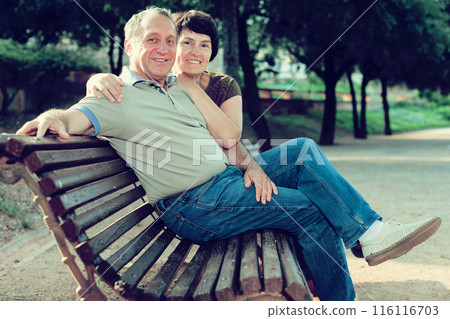 Middleaged male and female posing on bench Middleaged male and female posing on bench 116116703