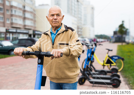 Portrait of elderly man with electric scooter on street 116116705
