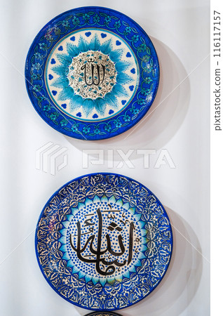 blue traditional Asian Uzbek ceramic plates hand-painted on white wall at a souvenir tableware shop in Uzbekistan blue traditional Asian Uzbek ceramic plates hand-painted on white wall at a souvenir tableware shop in Uzbekistan 116117157