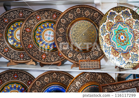 handmade Uzbek wooden souvenir plates with wood carvings hand-painted asian patterns in bazaar of Uzbekistan 116117299