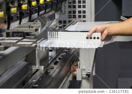 Close up the bending machine operator hold the sheet metal parts. 116117391