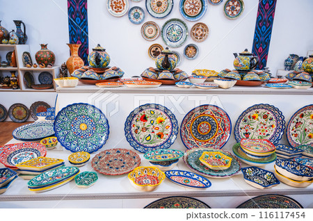 Arabic Uzbek ceramic plates and handmade tableware with hand-painted traditional Asian colorful patterns in market in Uzbekistan Arabic Uzbek ceramic plates and handmade tableware with hand-painted traditional Asian colorful patterns in market in Uzbekistan 116117454