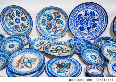 Uzbek handmade ceramic plates with hand-painted traditional ethnic Oriental Asian blue patterns in tableware store in Uzbekistan Uzbek handmade ceramic plates with hand-painted traditional ethnic Oriental Asian blue patterns in tableware store in Uzbekistan 116117551