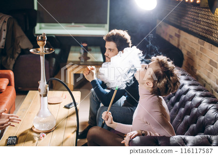 beautiful blond woman smoking while sitting with friends beautiful blond woman smoking while sitting with friends 116117587