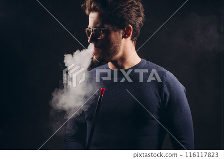 culture and tradition concept. young bearded man breathing out the shishas 116117823