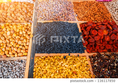 different varieties of dried fruits and nuts on counter of the East Asian food bazaar in Central Asia. Raisins, dried apricots, almonds, walnuts and figs in market stall different varieties of dried fruits and nuts on counter of the East Asian food bazaar in Central Asia. Raisins, dried apricots, almonds, walnuts and figs in market stall 116117850