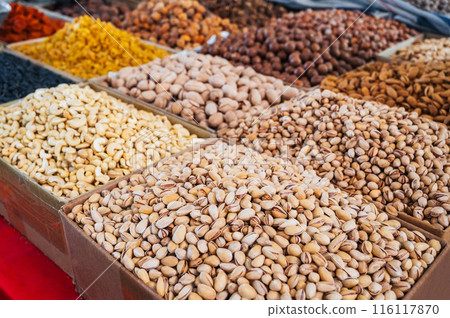 assortment of different variety nuts, dried fruits on counter at oriental Uzbek food bazaar. Almonds, raisins, pistachios, hazelnuts and cashews in market stall assortment of different variety nuts, dried fruits on counter at oriental Uzbek food bazaar. Almonds, raisins, pistachios, hazelnuts and cashews in market stall 116117870