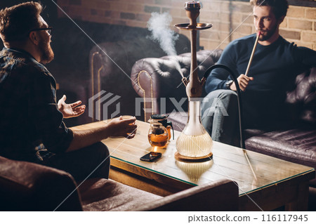 two businessmen are sitting on the sofas and having a chat 116117945