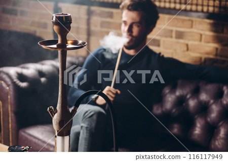 attractive young man in stylish clothes with hookah resting at the bar attractive young man in stylish clothes with hookah resting at the bar 116117949