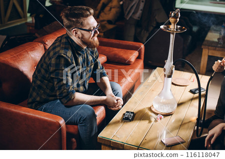 cherful ginger man in stylish clothes sitting on the sofa 116118047