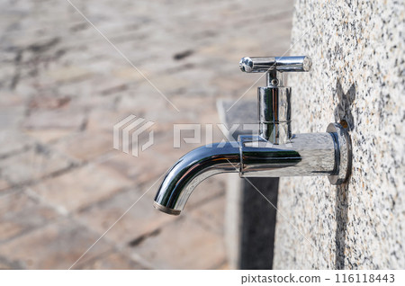 modern metal outdoor faucet with clean drinking water in park on street in the city in summer close-up 116118443
