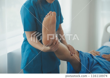 Physical therapists work with patients in close-up clinics. The concept of rehabilitation of physical health, the doctor gives advice to the patient. Ankle problems and muscle injuries Physical therapists work with patients in close-up clinics. The concept of rehabilitation of physical health, the doctor gives advice to the patient. Ankle problems and muscle injuries 116118974