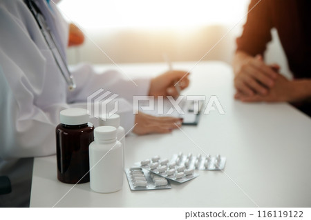 Doctor prescribing medicine giving pills to senior grandmother patient at hospital. 116119122