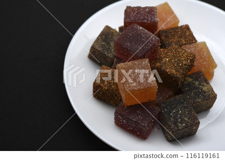Multicolored marmalade on a white plate. Sweets on a black background. Multicolored marmalade on a white plate. Sweets on a black background. 116119161