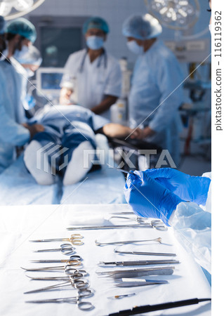 Surgical tools lying on table with nurse near and surgeons at background. Surgical tools lying on table with nurse near and surgeons at background. 116119362