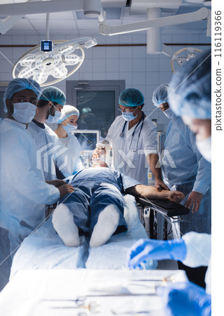Surgical tools lying on table with nurse near and surgeons at background. Surgical tools lying on table with nurse near and surgeons at background. 116119366