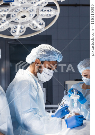 Medical Team Performing Surgical Operation in Bright Modern Operating Room Medical Team Performing Surgical Operation in Bright Modern Operating Room 116119399