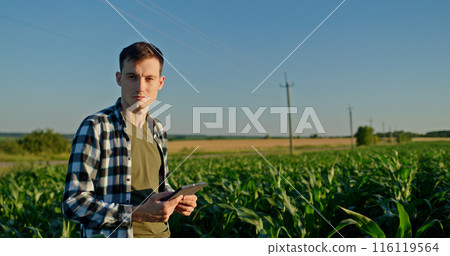Portrait of an attractive young farmer against a rural landscape, looking confidently at the camera Portrait of an attractive young farmer against a rural landscape, looking confidently at the camera 116119564
