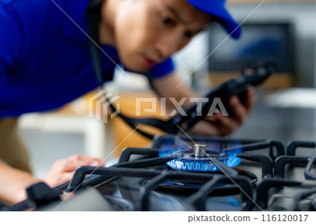 A man in work clothes checking a gas stove 116120017