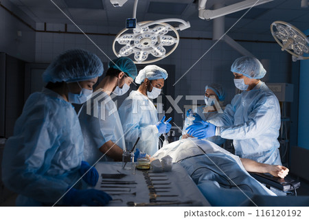 Surgical tools lying on table with nurse near and surgeons at background. Surgical tools lying on table with nurse near and surgeons at background. 116120192