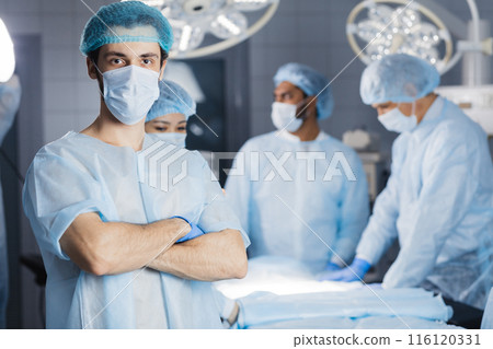 Surgeon looking at camera with colleagues 116120331