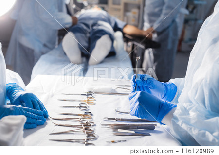 Surgical tools lying on table with nurse near and surgeons at background. Surgical tools lying on table with nurse near and surgeons at background. 116120989